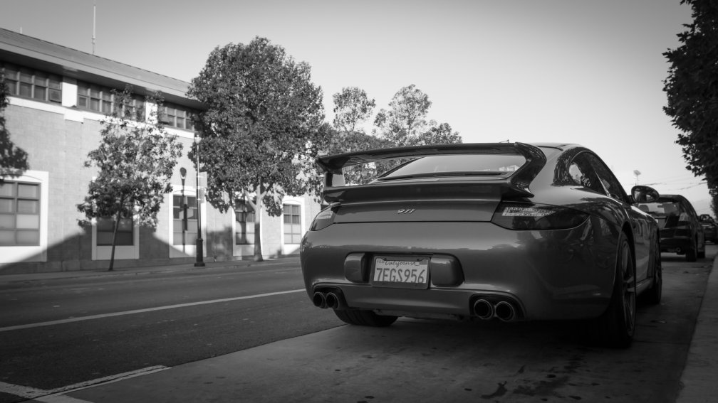 A rear quarter shot of a Porsche 911 parked by the side of a city street.